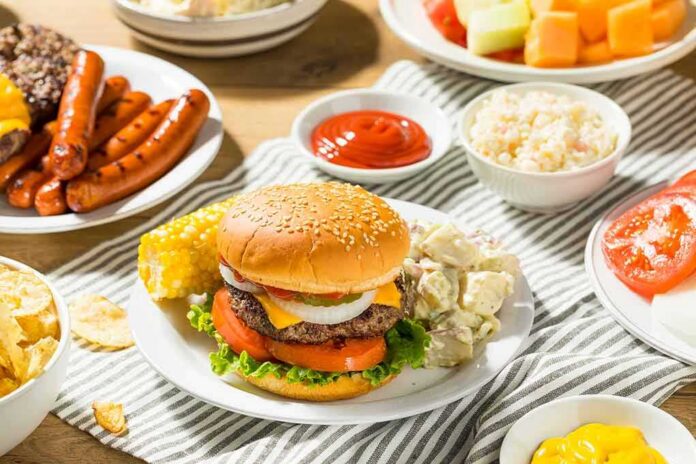 Cheeseburger on a plate with potato salad and corn on the cob