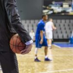 Courtside Chaos: NBA Star Chucked Out Basketball coach in suit holding ball courtside