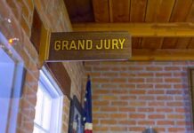 Juror ATTACKED For Being A Republican Grand jury sign in a brick-walled hallway