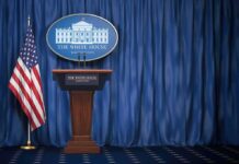 Trump BANS CNN, Politico and MSN From White House White House press briefing podium with U.S. flag and blue curtain