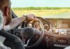 Driver's hands on steering wheel of car interior
