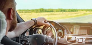 Driver's hands on steering wheel of car interior