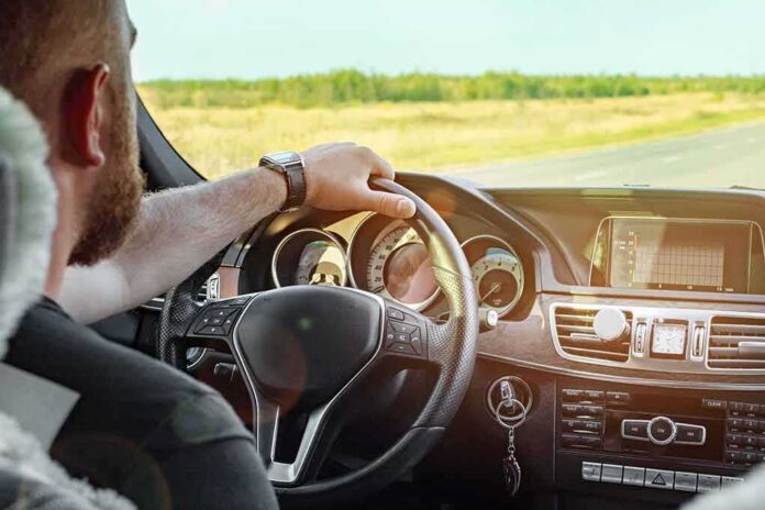 shutterstock_1240838257 Driver's hands on steering wheel of car interior