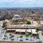 historic mosque with domes and minaret overlooking a busy city square