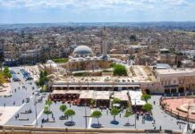 historic mosque with domes and minaret overlooking a busy city square