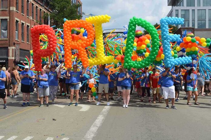Dontrelle Inman at a Pride parade holding balloon letters spelling PRIDE