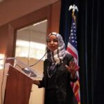ICE Moves On Omar — Trump Confirms Ilhan Omar speaking at a podium with a microphone