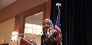 Ilhan Omar speaking at a podium with a microphone