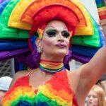 Drag performer in vibrant rainbow costume at a parade