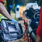 Paramedic with defibrillator beside patient on stretcher