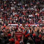 Speaker at podium addressing large crowd in arena