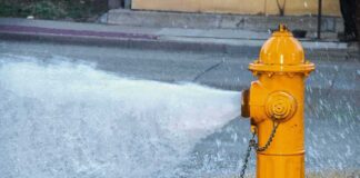 Yellow fire hydrant gushing water onto a street
