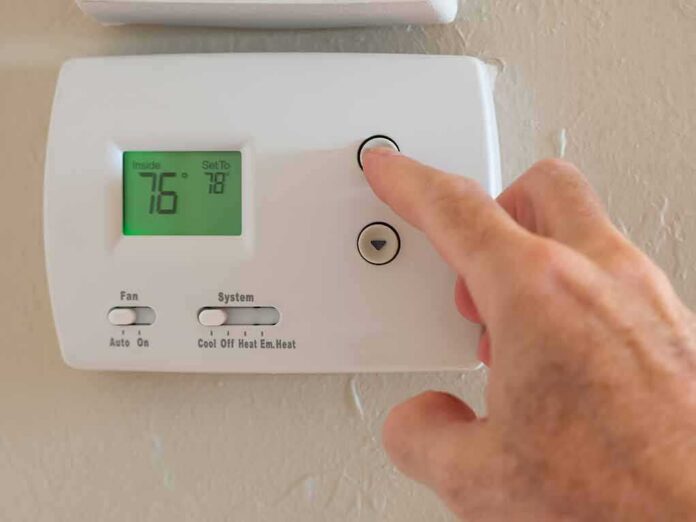 shutterstock_1658987455 Hand adjusting a digital thermostat on a wall