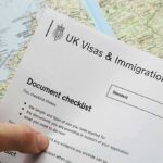 Government Issues Guides to Illegals Telling Them Not to Rape Women Hand holding UK visa and immigration document checklist over a map