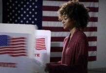 Voter at a polling booth with an American flag backdrop