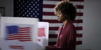 Voter at a polling booth with an American flag backdrop