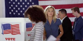 Voters at polling booths in front of an American flag