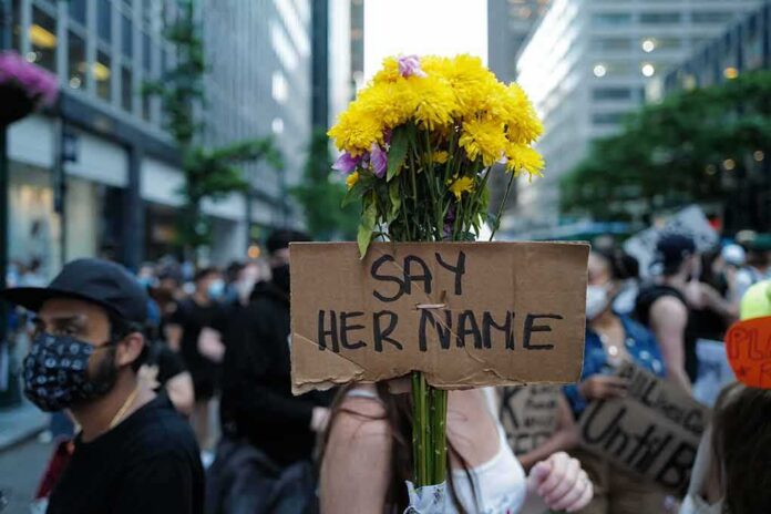 Protester holding flowers and a cardboard sign in a city street
