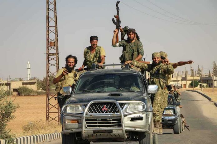 shutterstock_1779972902 armed men riding on pickup trucks in a convoy