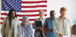 Voters standing in line at a polling station with a U.S. flag