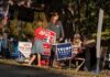 People at a campaign booth with political signs outdoors
