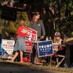 People at a campaign booth with political signs outdoors