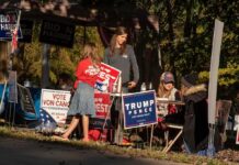 People at a campaign booth with political signs outdoors