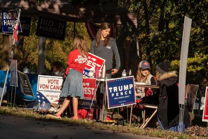 People at a campaign booth with political signs outdoors