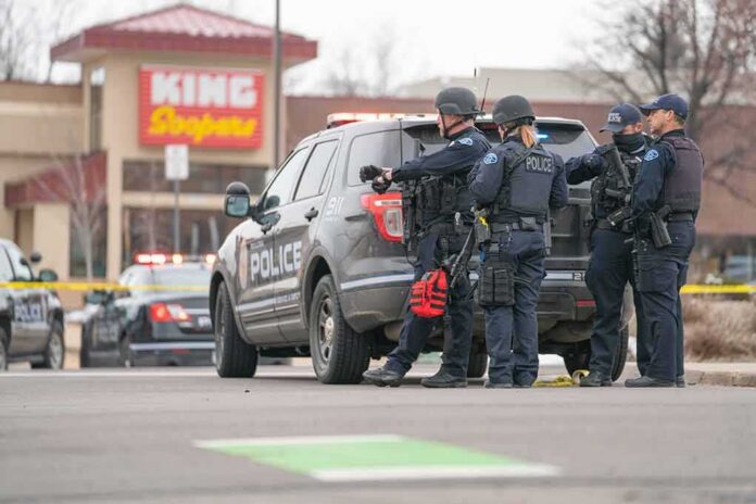 shutterstock_1941371278 Police officers gather beside a patrol SUV at a taped-off scene