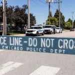Police line barrier blocking a street with patrol vehicles behind