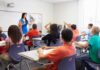 Teacher leading classroom discussion with students raising hands