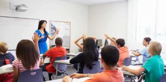 Teacher leading classroom discussion with students raising hands