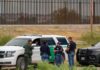 100MPH Police Chase Causes Complete CHAOS law enforcement officers confer beside patrol vehicles near a border fence