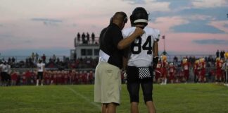 football coach with arm around player number 84 on sideline