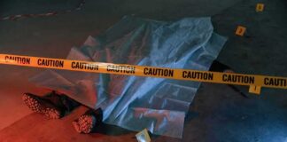 crime scene body under sheet behind caution tape