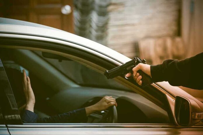 armed person pointing a gun at a driver in a car