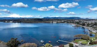 Aerial view of a lakeside town with pier and boats under a blue sky