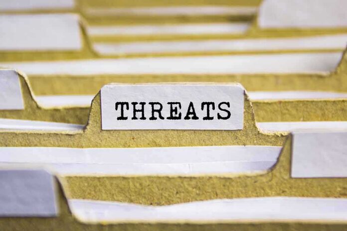 shutterstock_525112936 index tab labeled threats in a filing organizer
