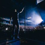 Singer on stage facing a large concert crowd