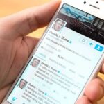 hand holding smartphone showing a social media profile