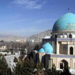 Blue-domed mosque with mountains in the background