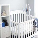 White baby crib with mobile in a bright nursery