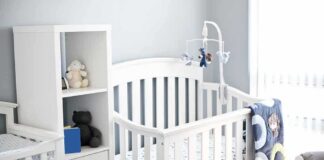 White baby crib with mobile in a bright nursery