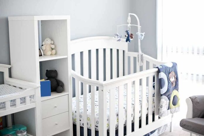 shutterstock_753586648 White baby crib with mobile in a bright nursery