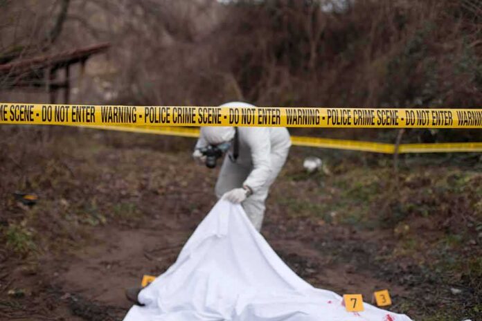 forensic investigator at outdoor crime scene behind caution tape
