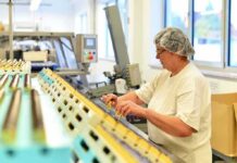 Worker in hair net inspects items on a factory conveyor line