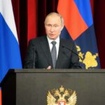 SECOND Person Dies in Russia Plague Outbreak Vladimir Putin speaking at a podium with microphones