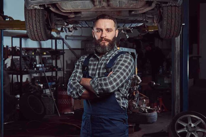 Auto mechanic standing with arms crossed in a garage