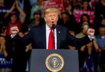 Rap Icon Joins Trump On-Stage During Michigan Rally Donald Trump speaking at a rally podium with arms raised