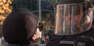 protester faces police officer in riot gear